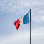 The French national flag waving against a blue sky in Paris, France.